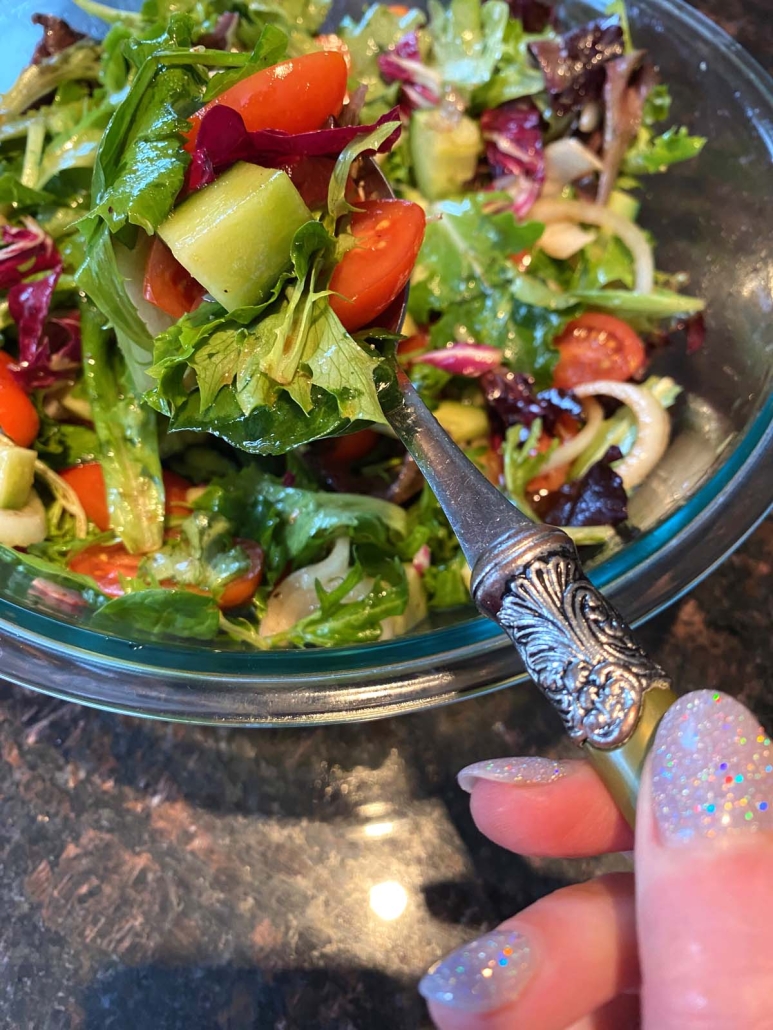 hand holding forkful of Spring Mix Salad