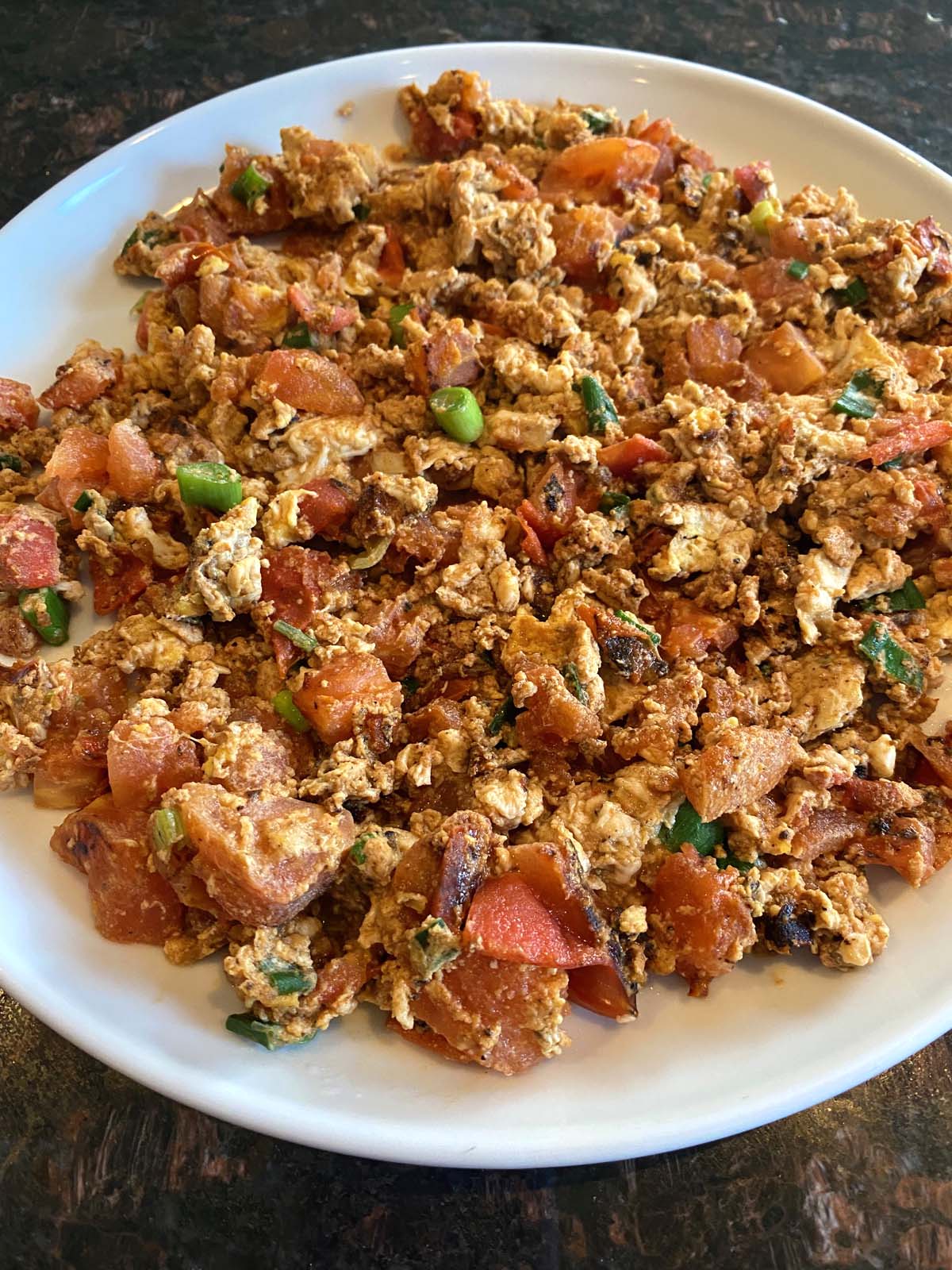 Chinese egg tomato stir fry on a white plate. 