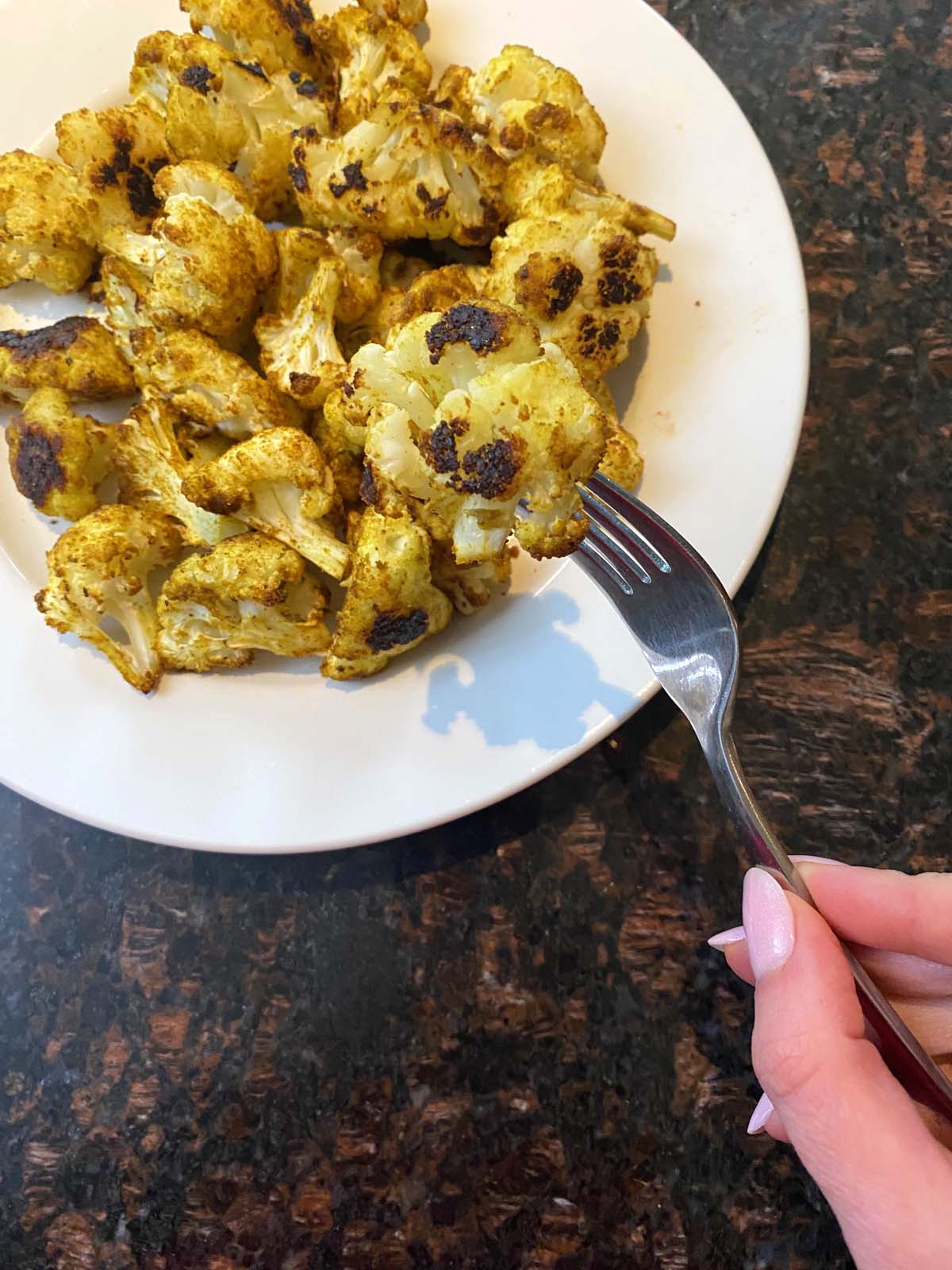 Roasted curried cauliflower on a white plate. 