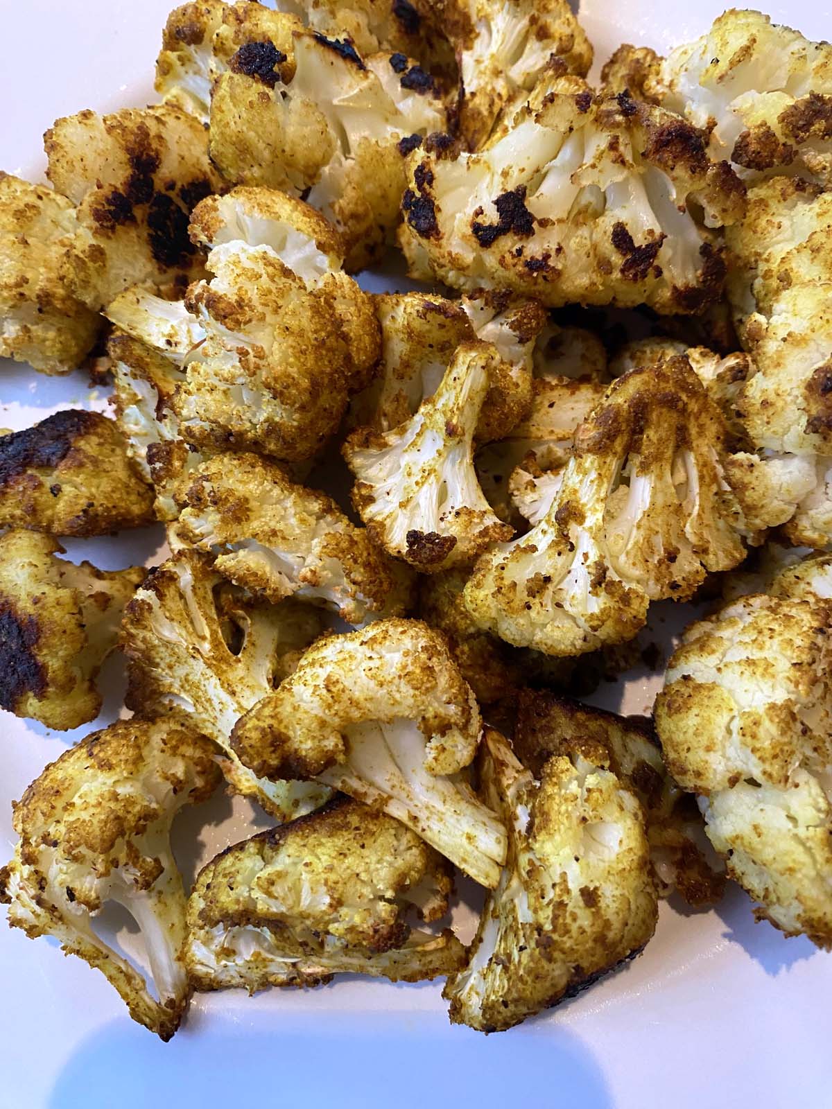 Roasted curried cauliflower on a white plate. 