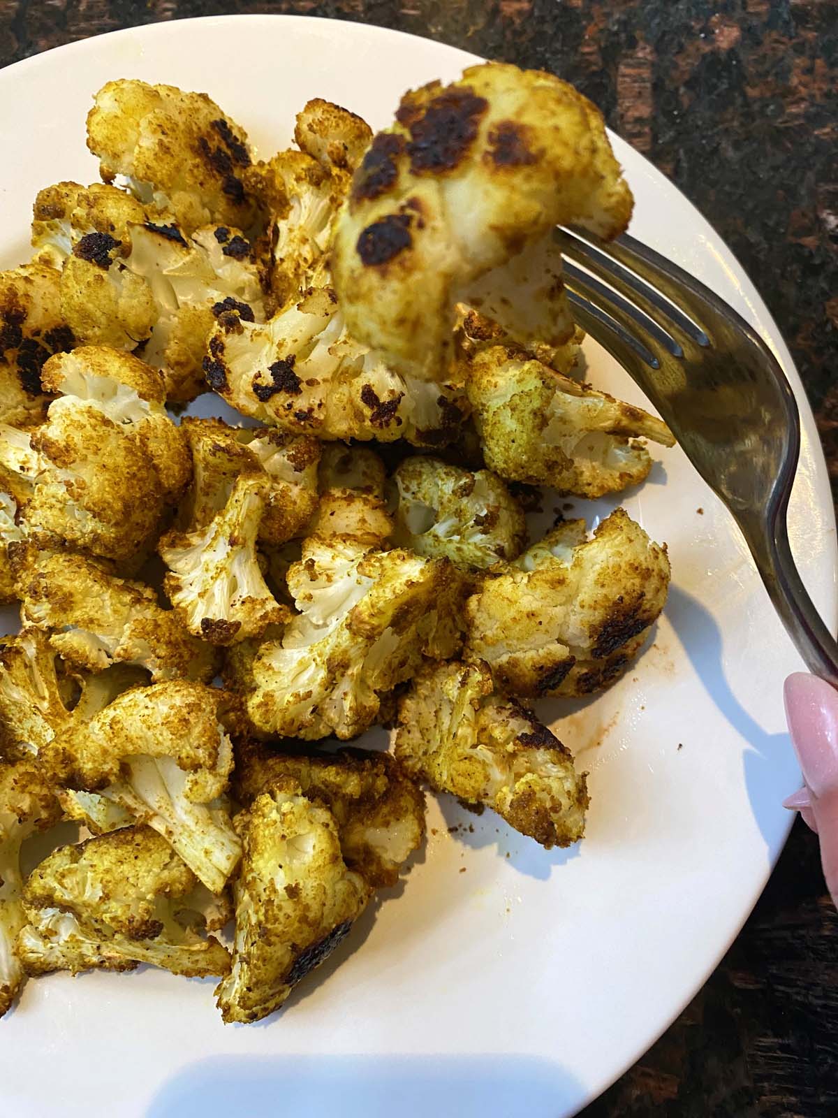 Roasted curried cauliflower on a white plate. 