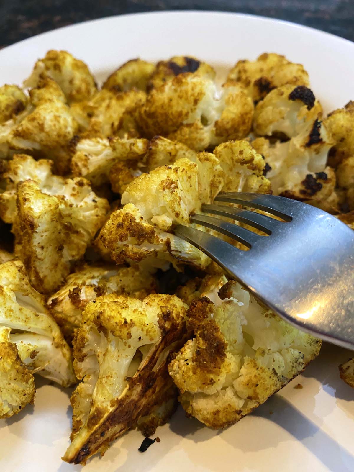 Roasted curried cauliflower on a white plate. 