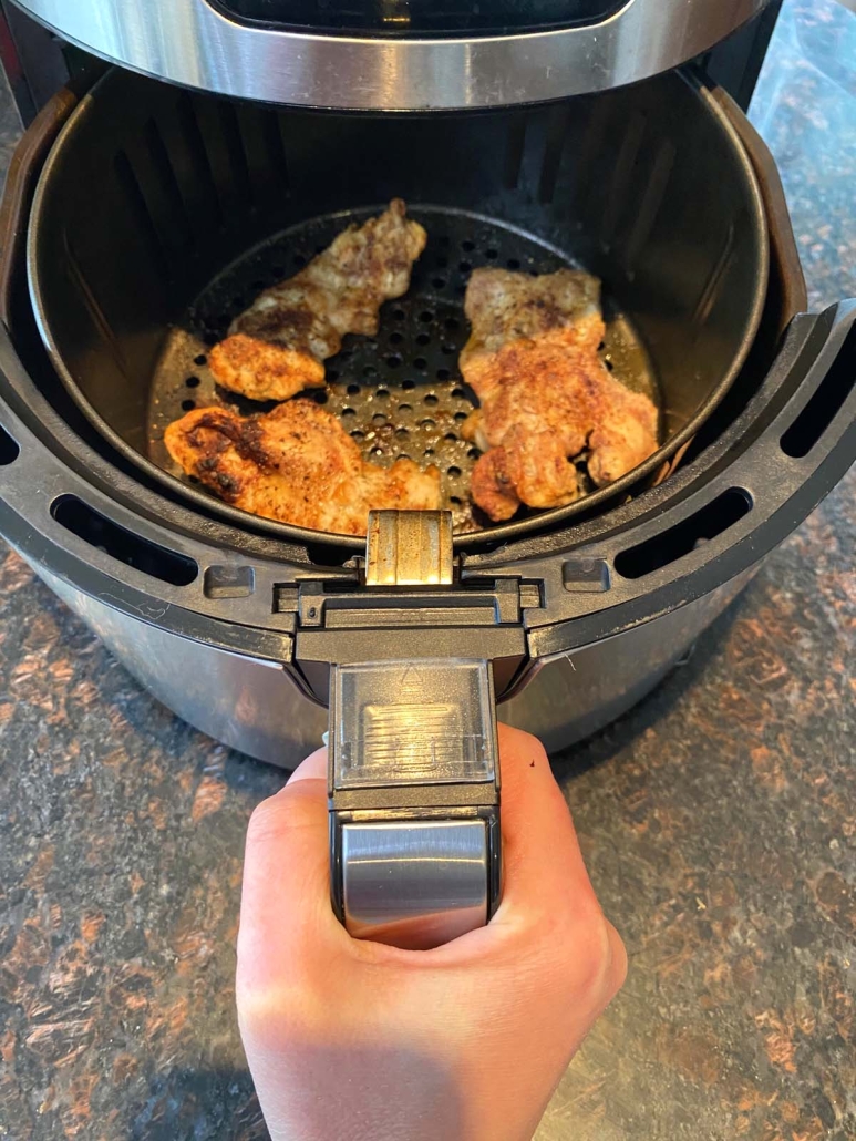 air fryer opened to show cooking chicken thighs