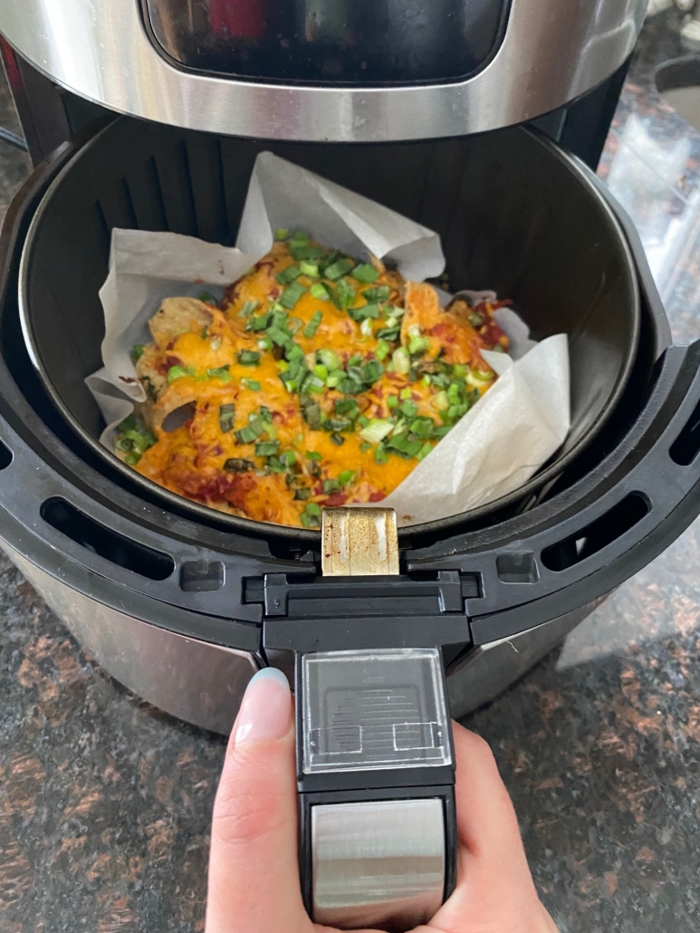 hand holding air fryer open to show cooked nachos