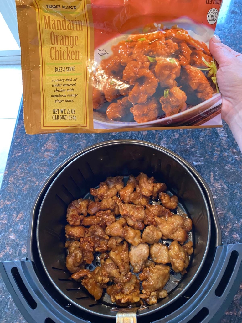 Trader Joe’s Orange Chicken in air fryer next to package of frozen orange chicken