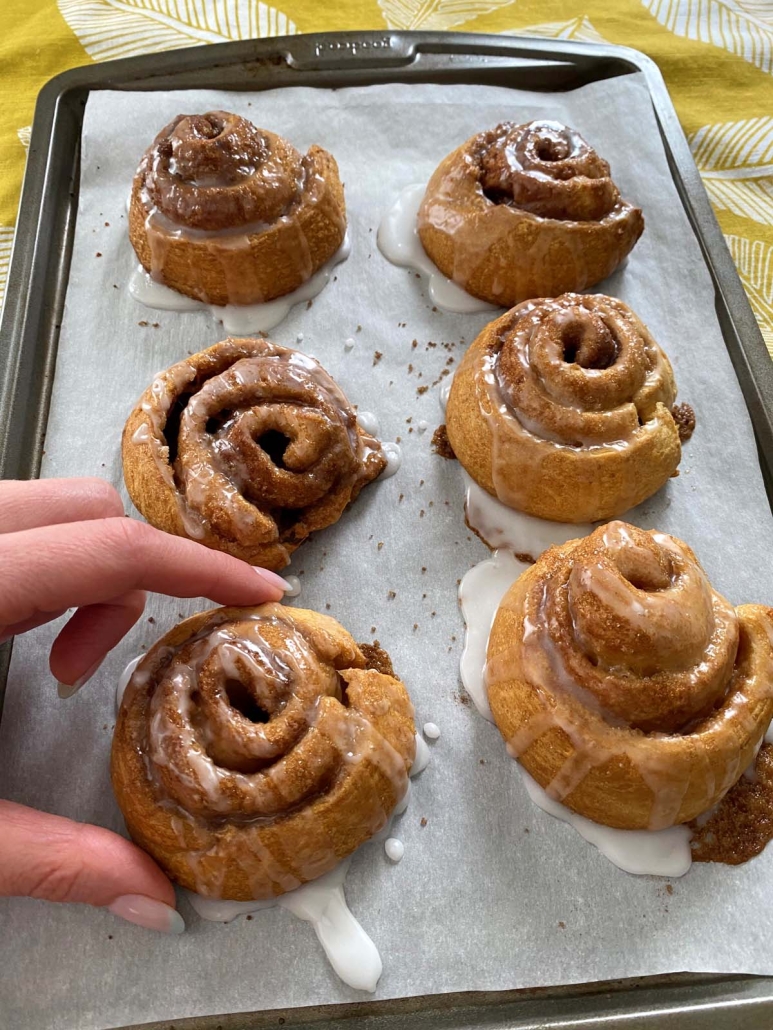 hand holding golden brown Crescent Roll Cinnamon Roll