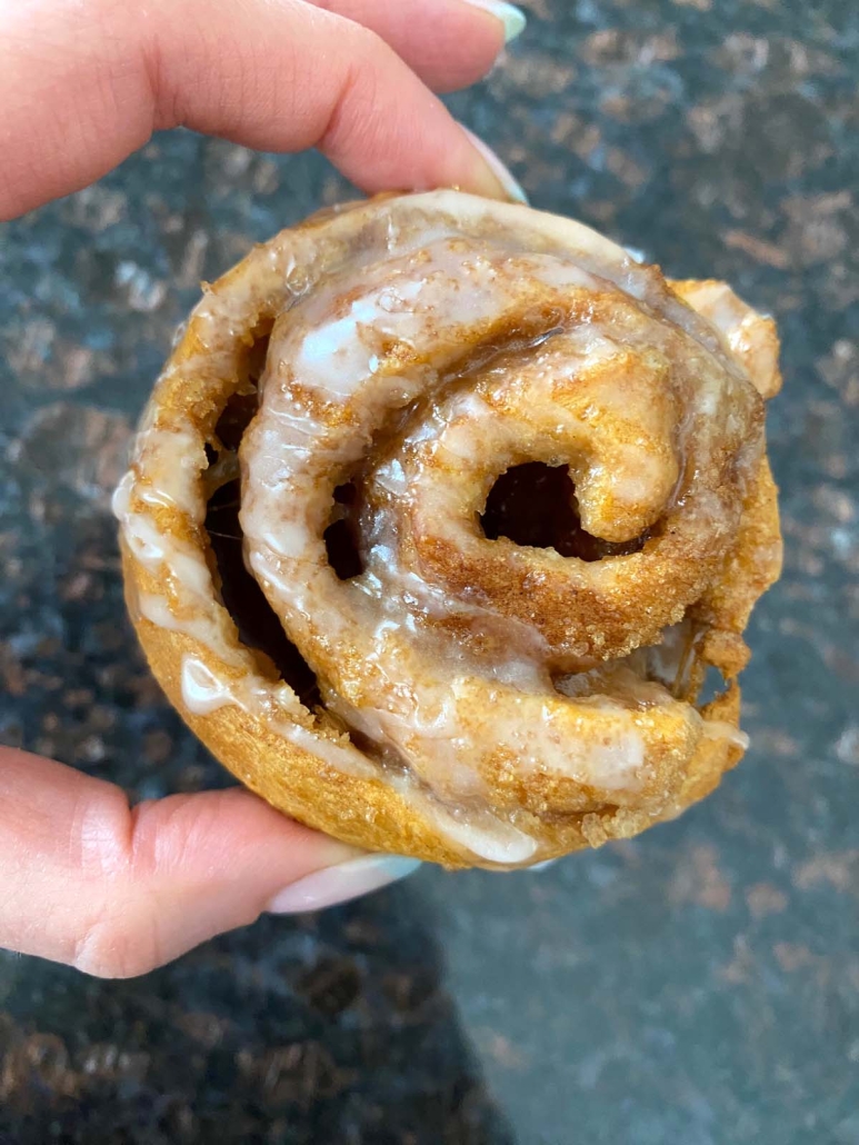 hand holding an iced Crescent Roll Cinnamon Roll