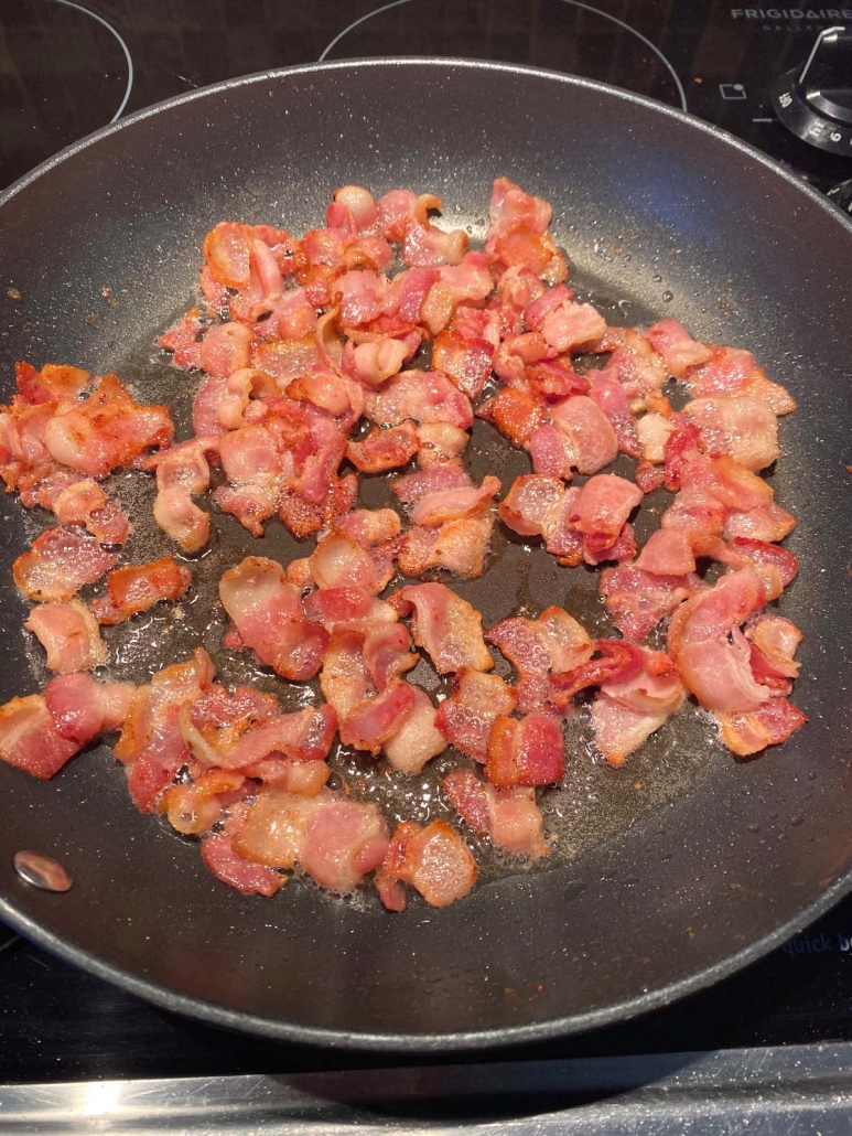 bacon pieces cooking in a skillet