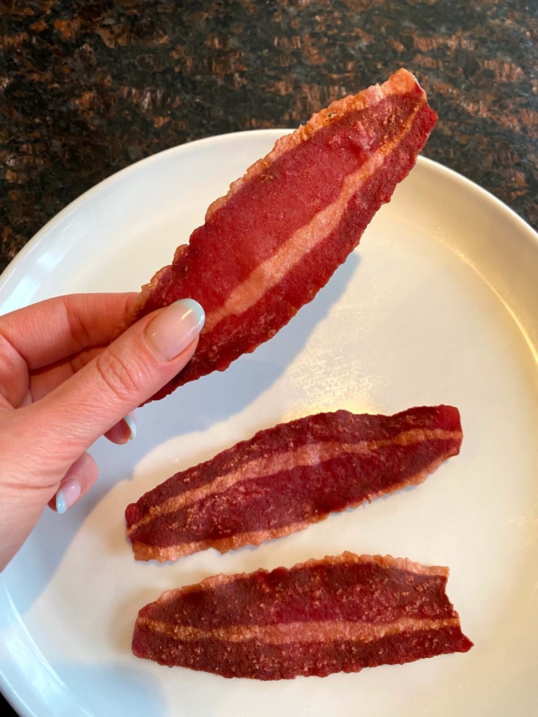 hand holding slice of microwave turkey bacon
