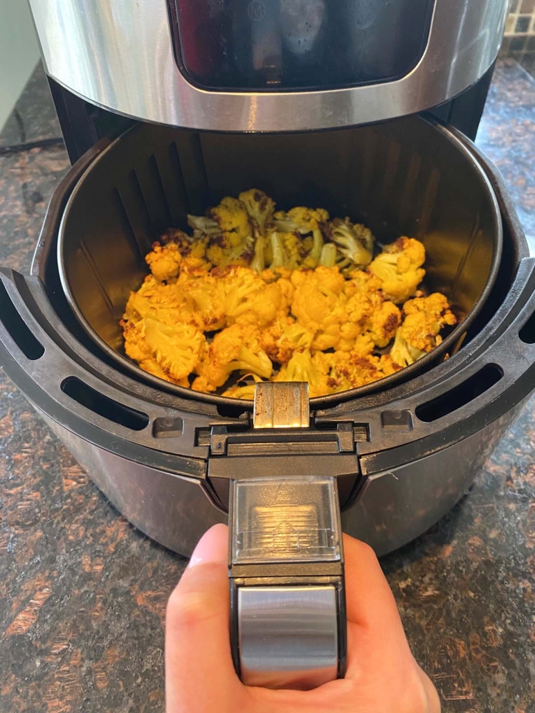 air fryer opened to show cooking orange cauliflower