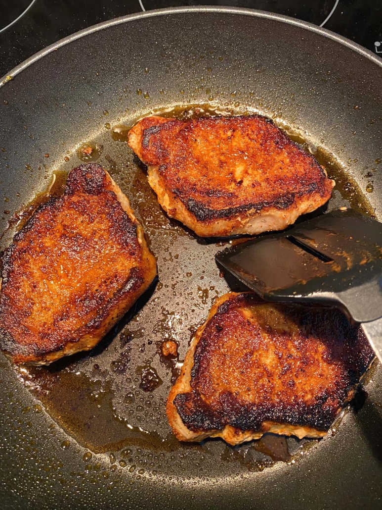 spatula flipping pork chops in a skillet