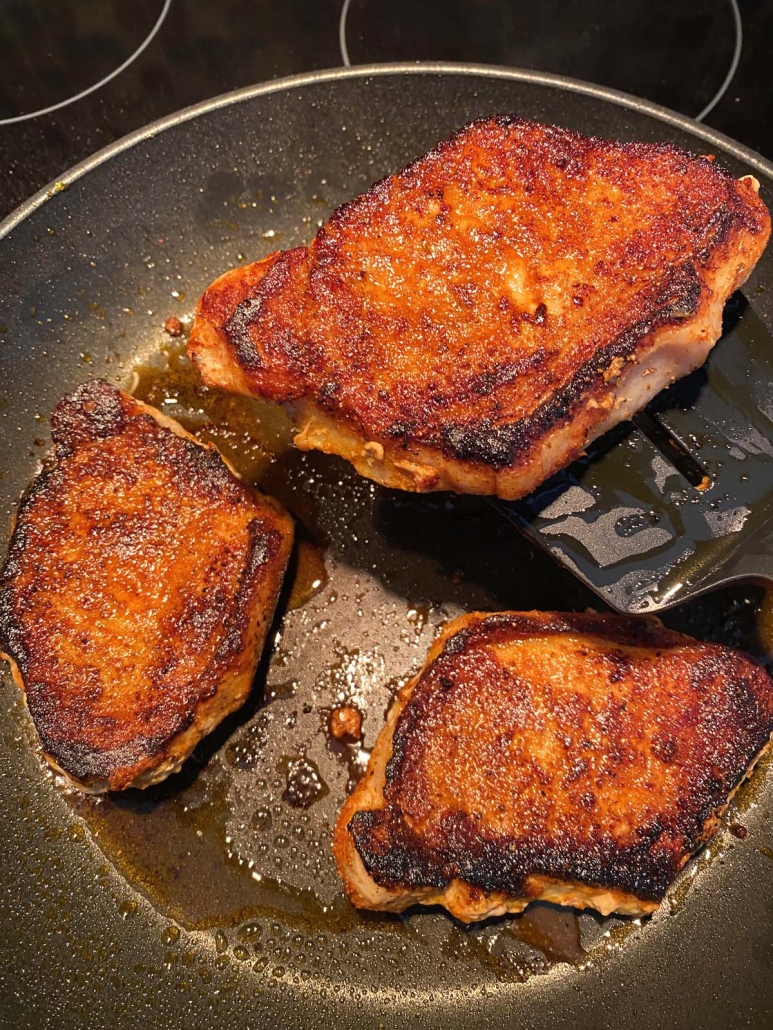 seasoned pork chops cooking in a skillet