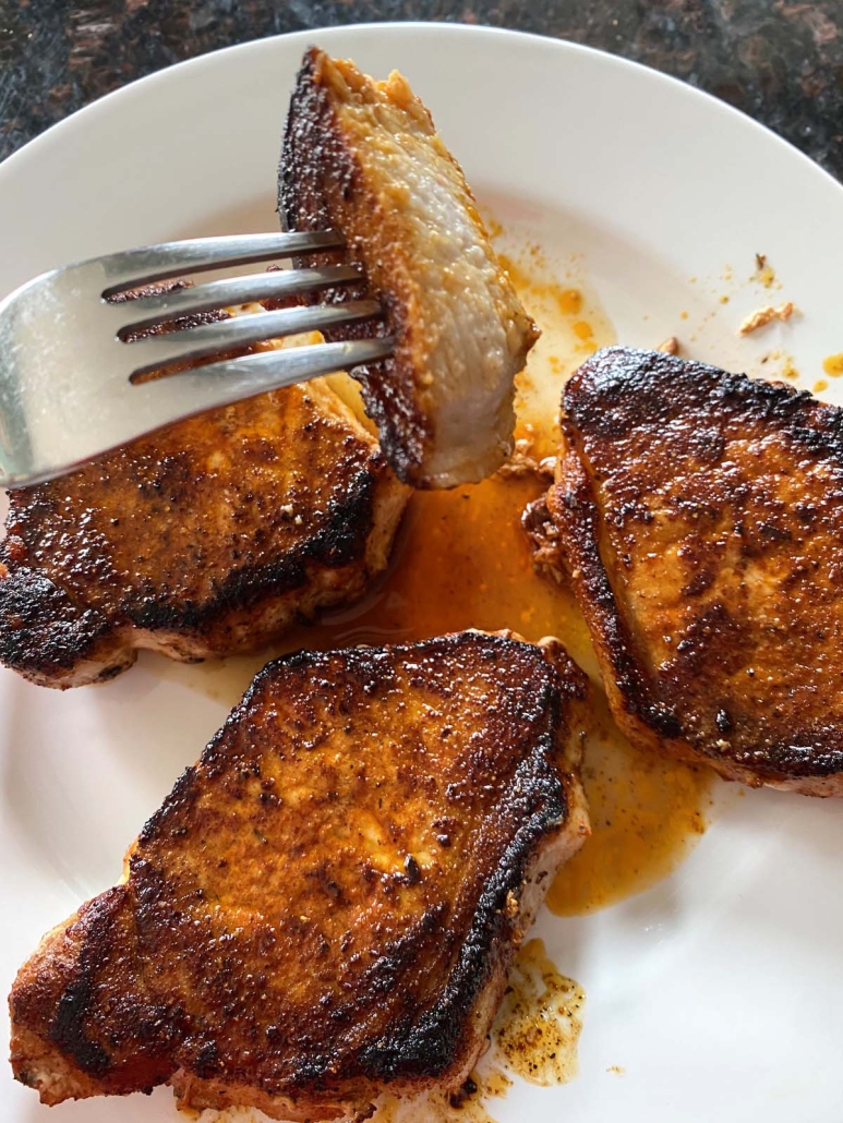 fork holding piece of seasoned, Sauteed Pork Chops