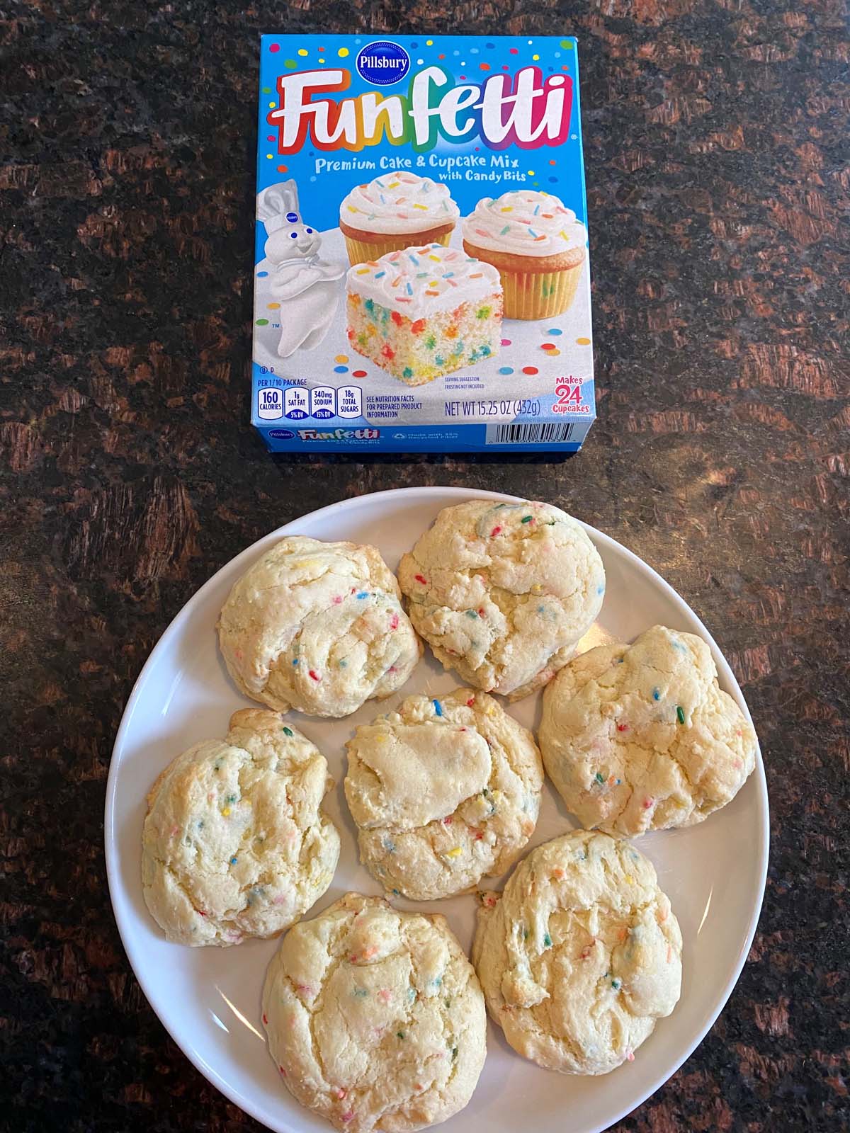 Funfetti cake mix cookies on a white plate and a box of funfetti cake mix.