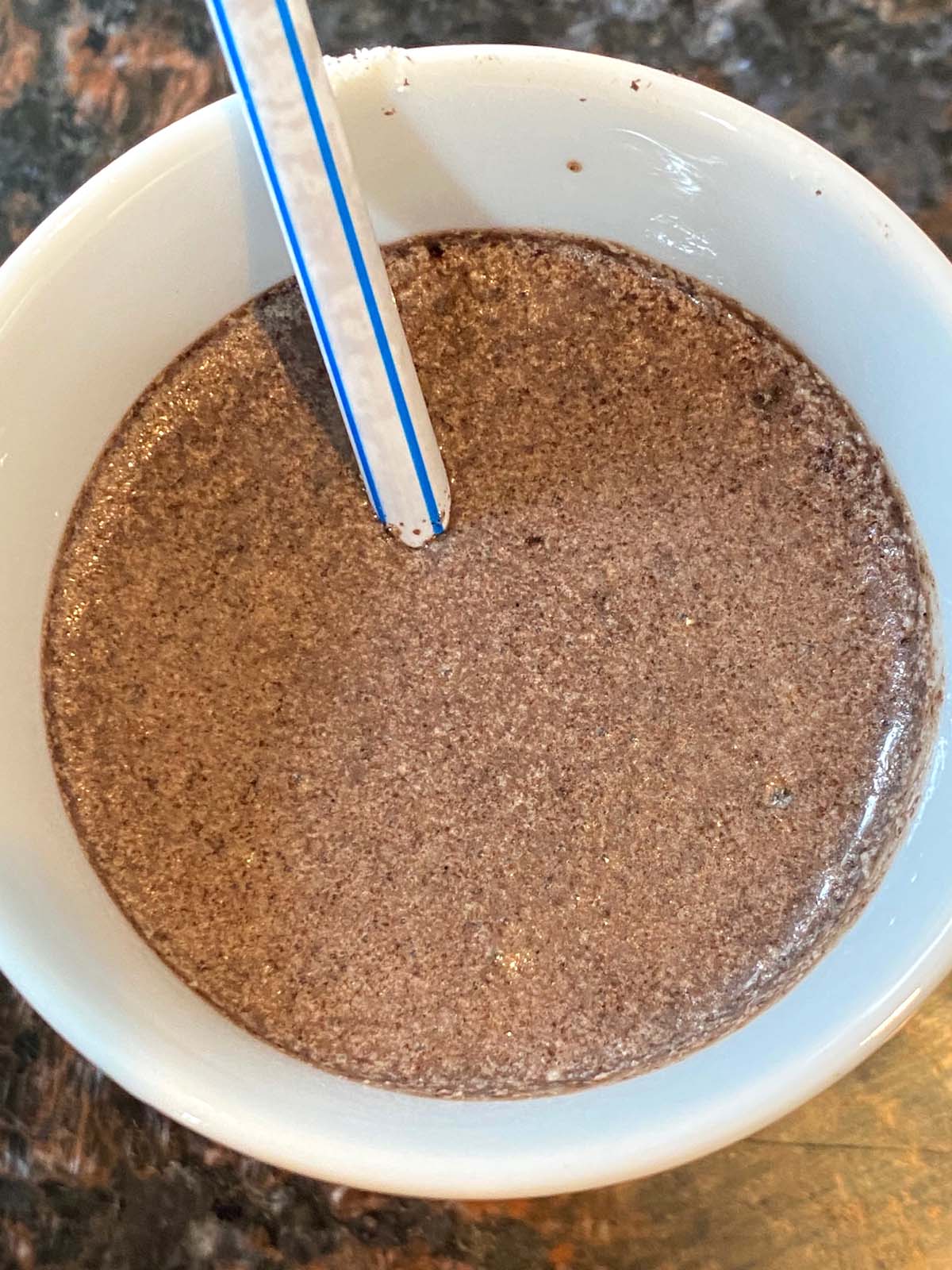 Oreo milkshake in a mug with a straw.