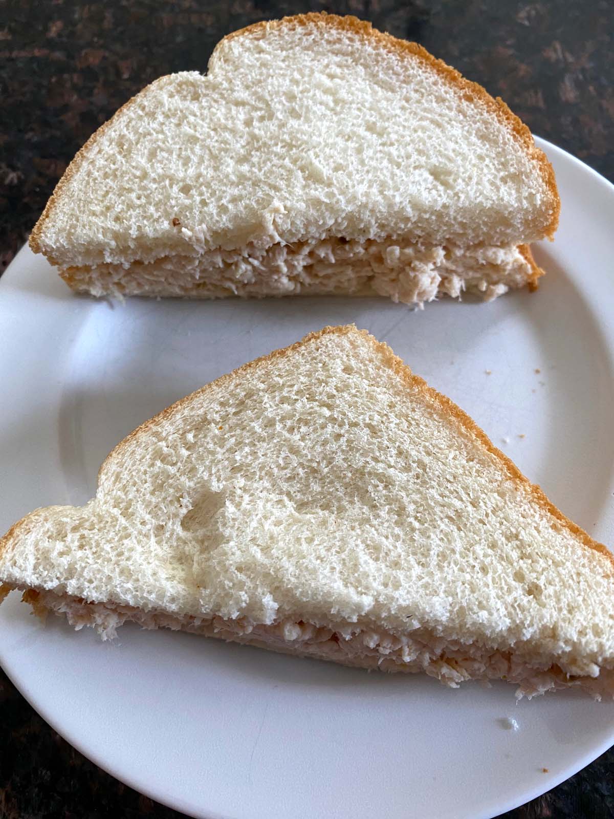 Shredded chicken sandwich on a white plate. 