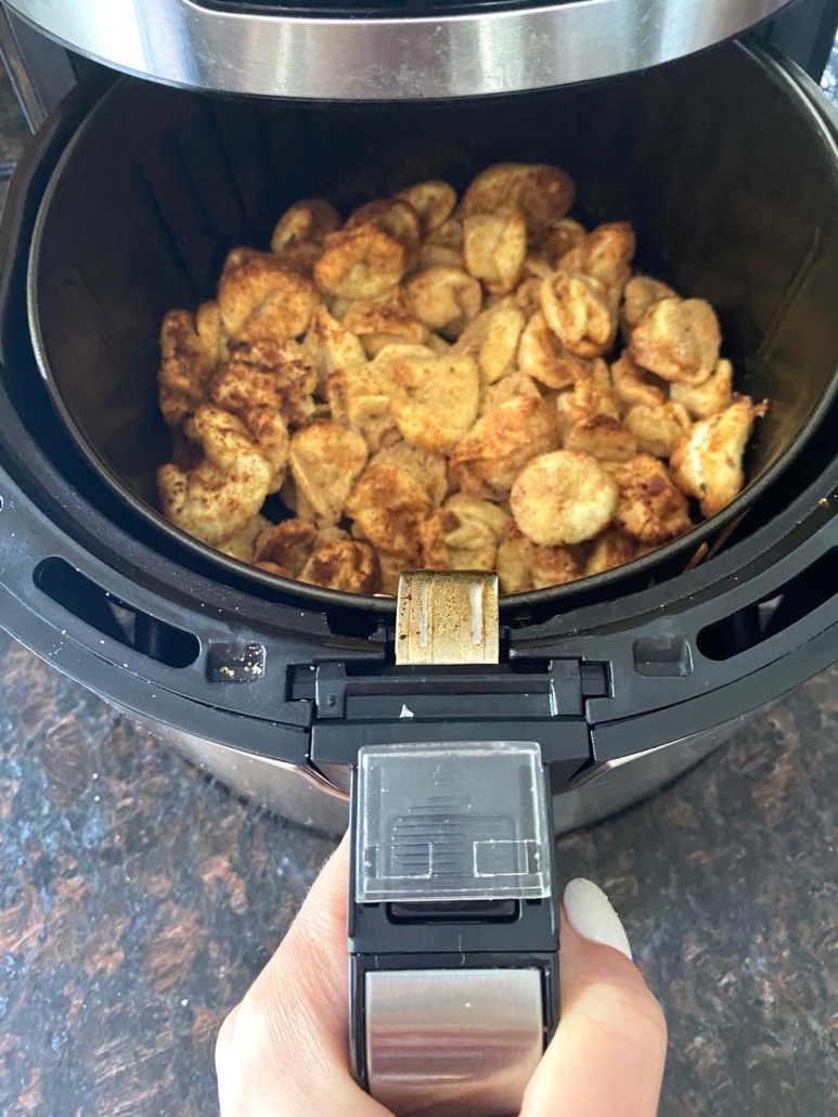 hand holding air fryer basket with Air Fryer Tortellini inside