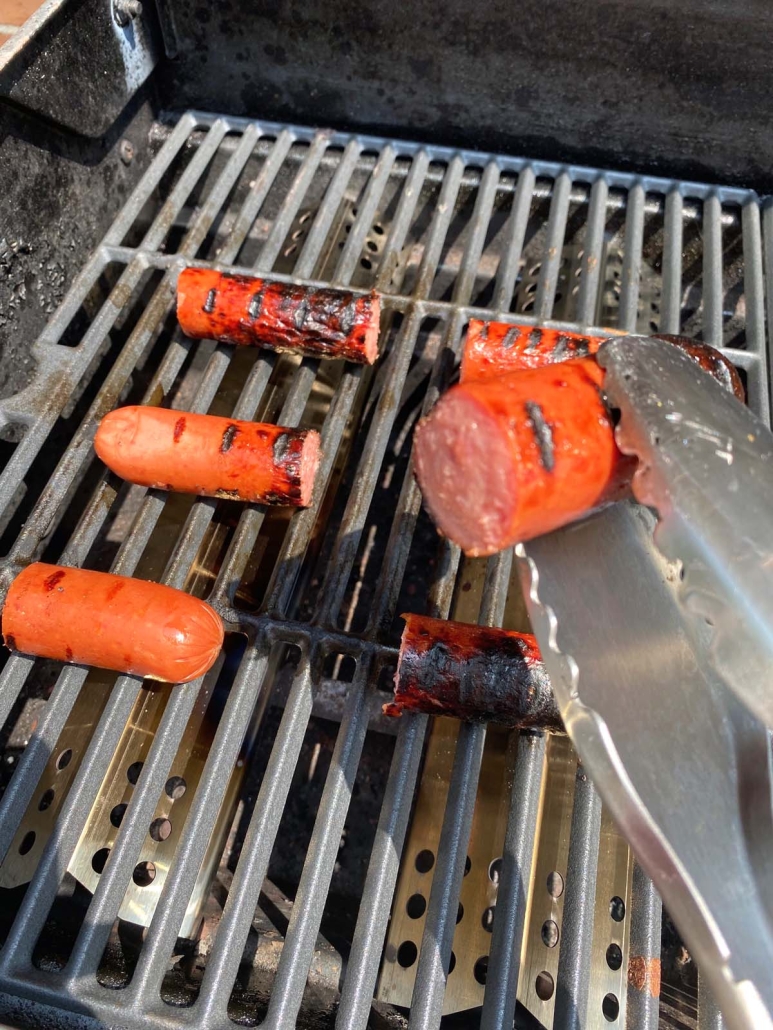 tongs holding piece of Grilled Kielbasa Polish Sausage