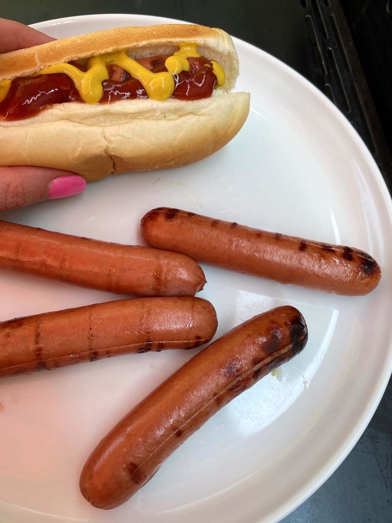 hand holding grilled hot dog in a bun