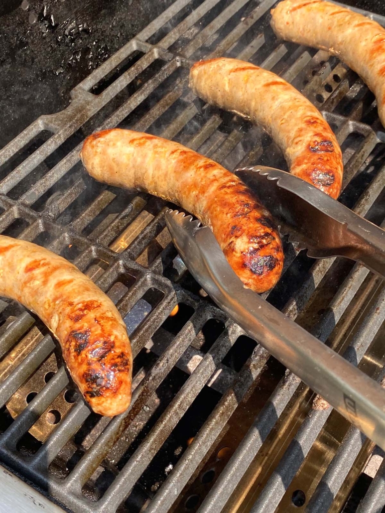 tongs taking Italian Sausage off of grill