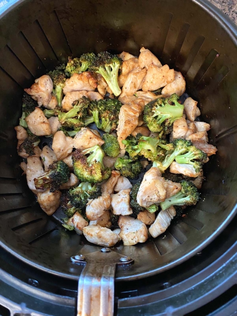 air fryer basket with chopped chicken and broccoli inside