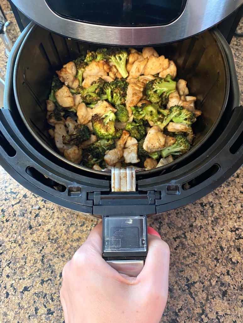 air fryer opened to show chicken and broccoli cooking inside