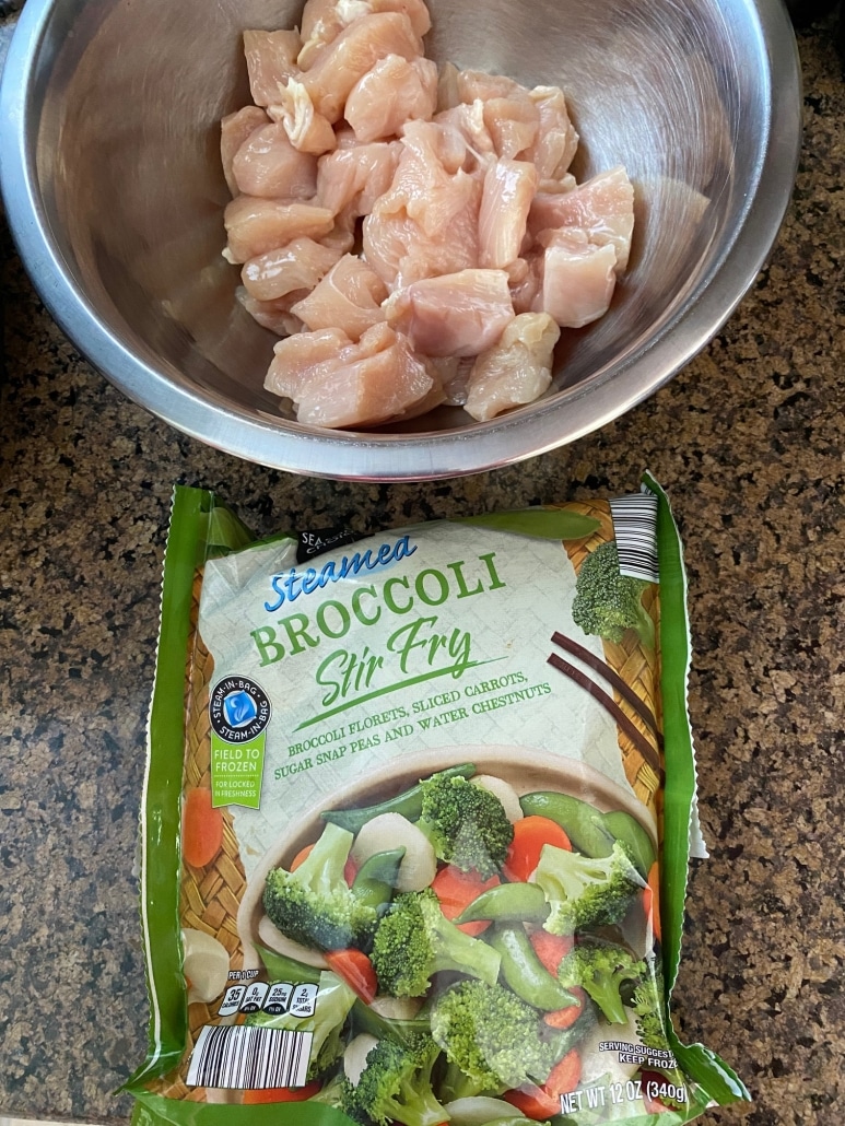 bowl of raw chicken next to package of frozen vegetables