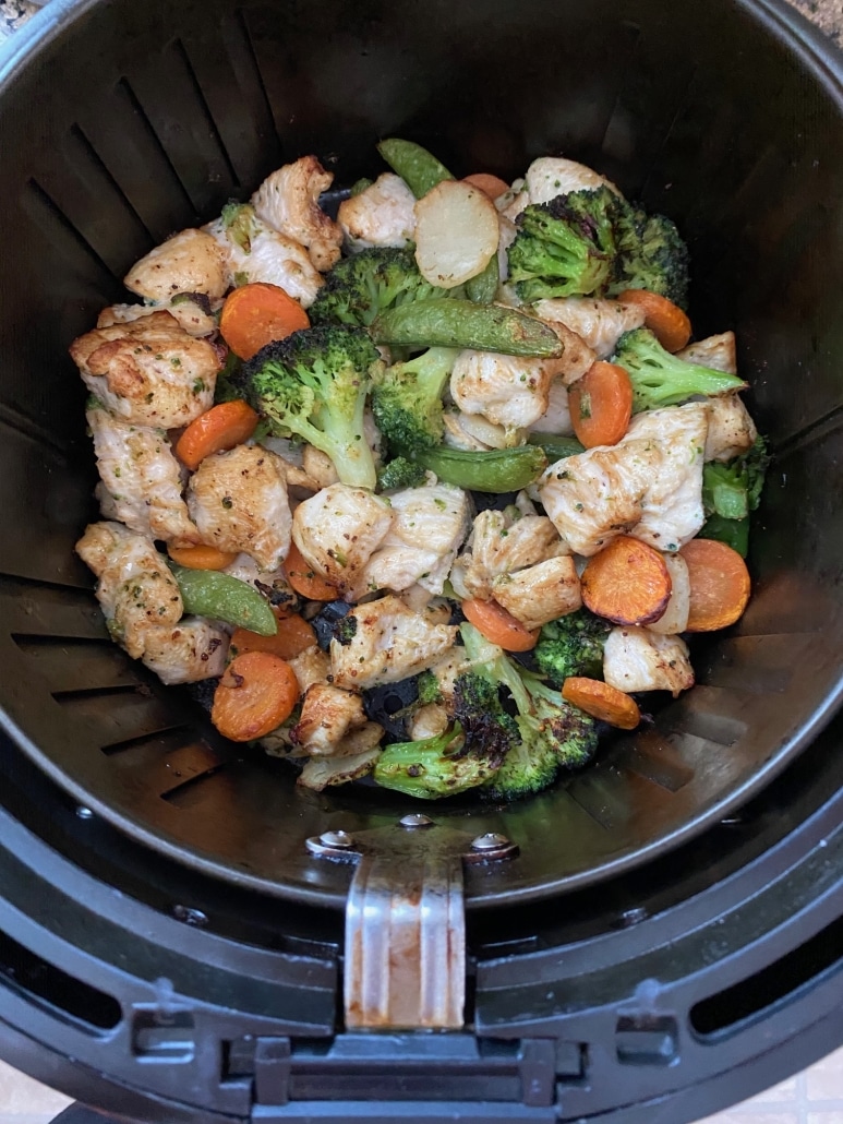 chicken and vegetables cooking in air fryer basket