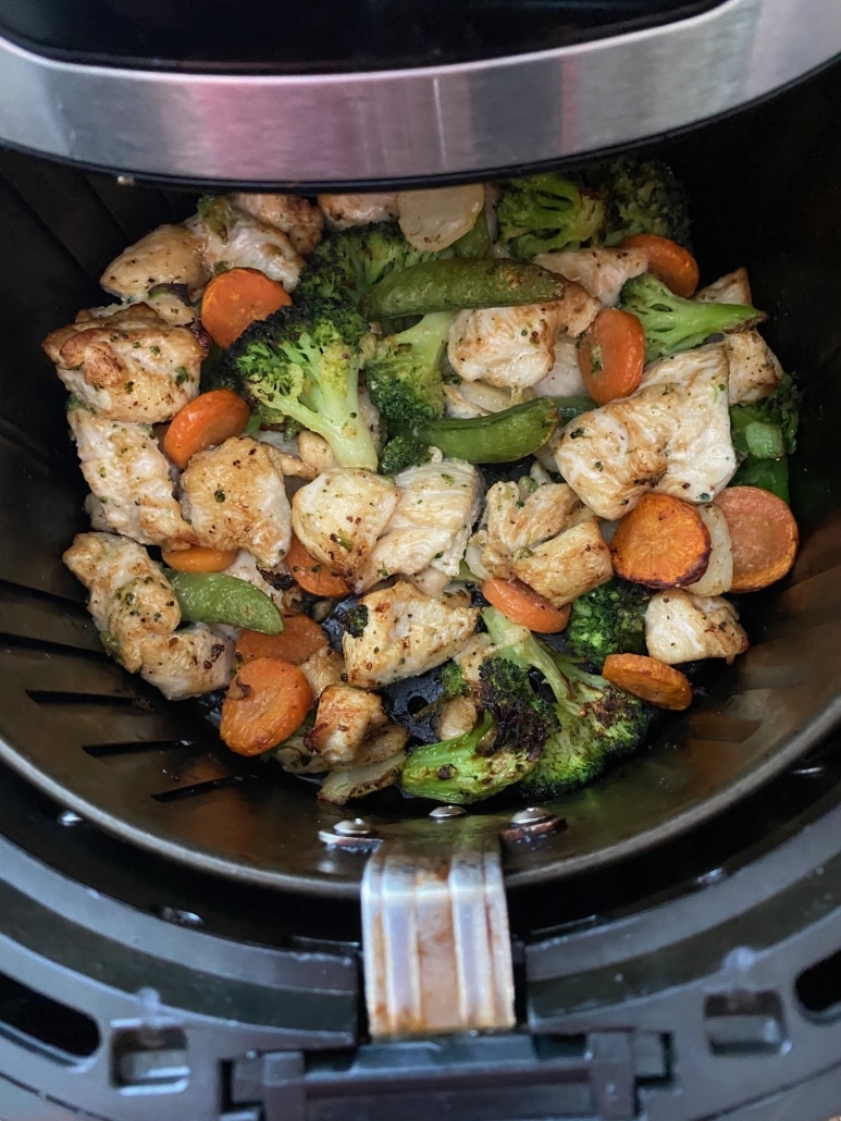 air fryer opened to show chicken and vegetables