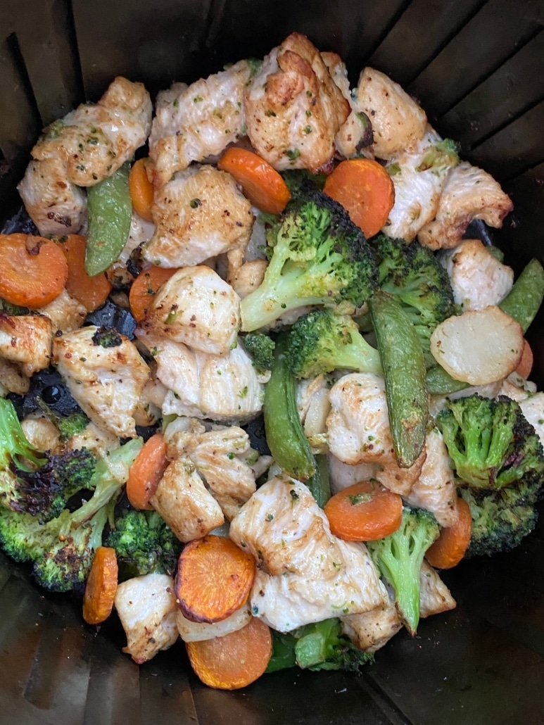 air fryer basket with easy dinner chicken and vegetables inside