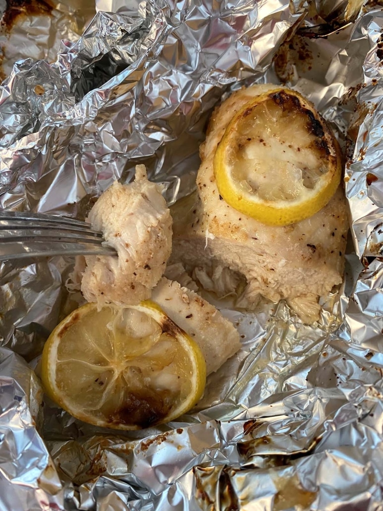 fork holding piece of air fryer chicken breast cooked in foil