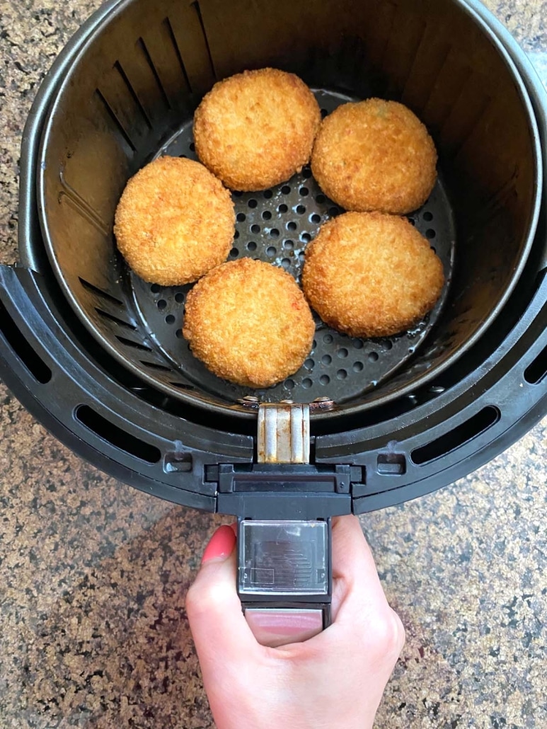 hand holding air fryer basket with easy dinner lobster cakes inside