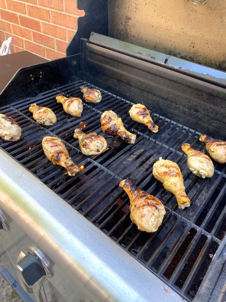 grill opened to show chicken drumsticks cooking