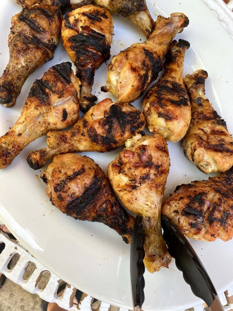 bbq tongs holding grilled piece of chicken