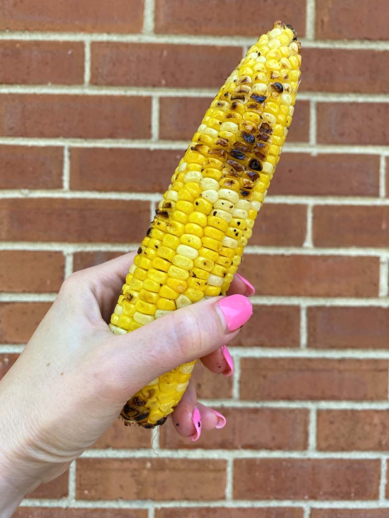 hand holding grilled corn cob