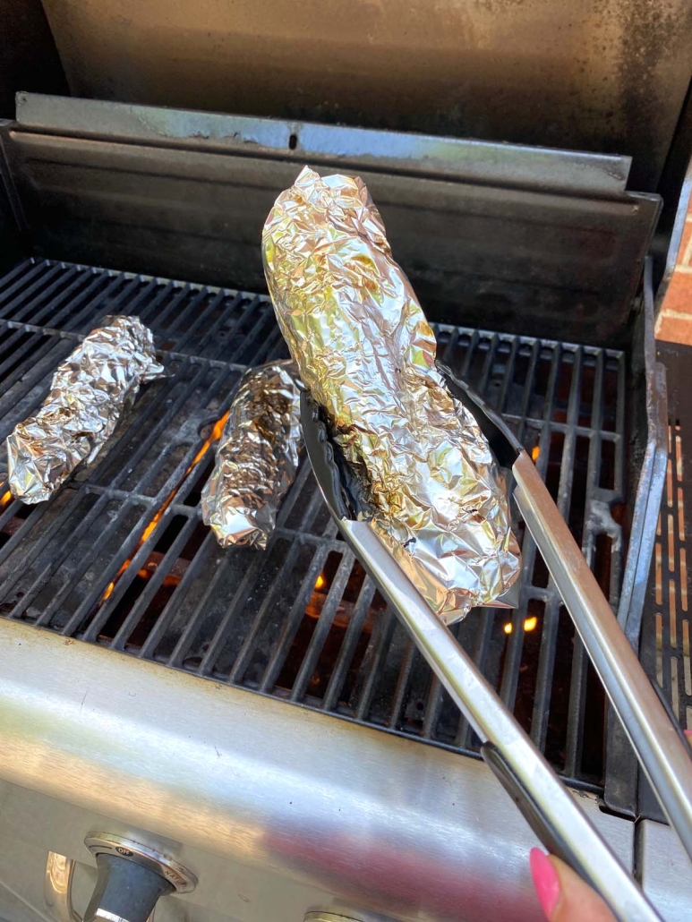 tongs holding Grilled Corn In Foil