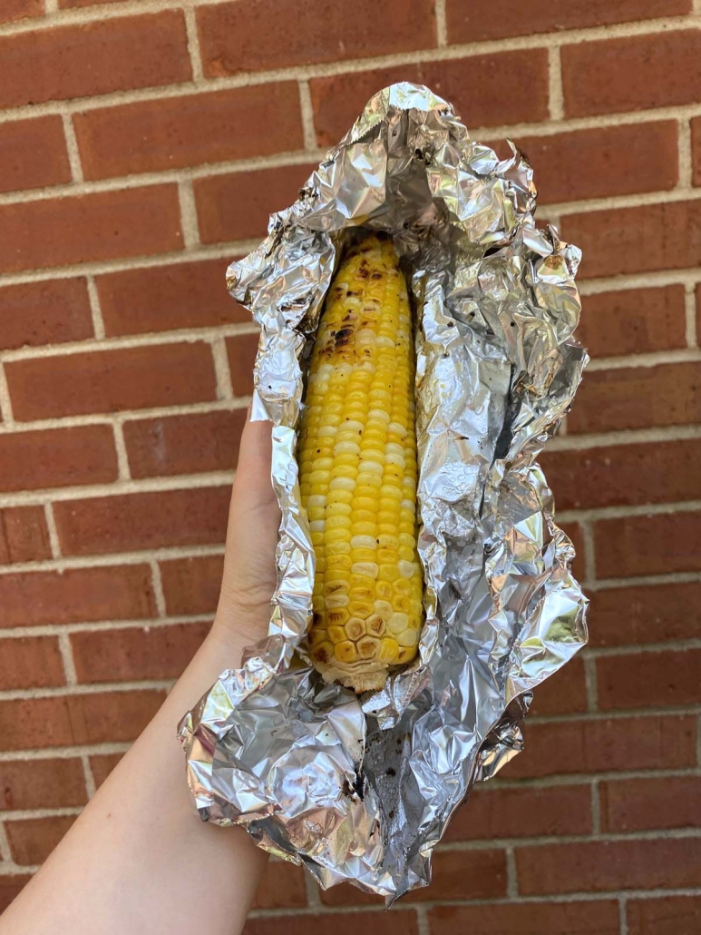 hand holding corn cob wrapped in foil