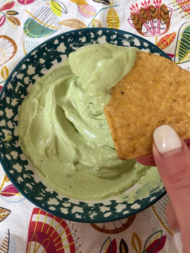 tortilla chip dipped into Avocado Crema