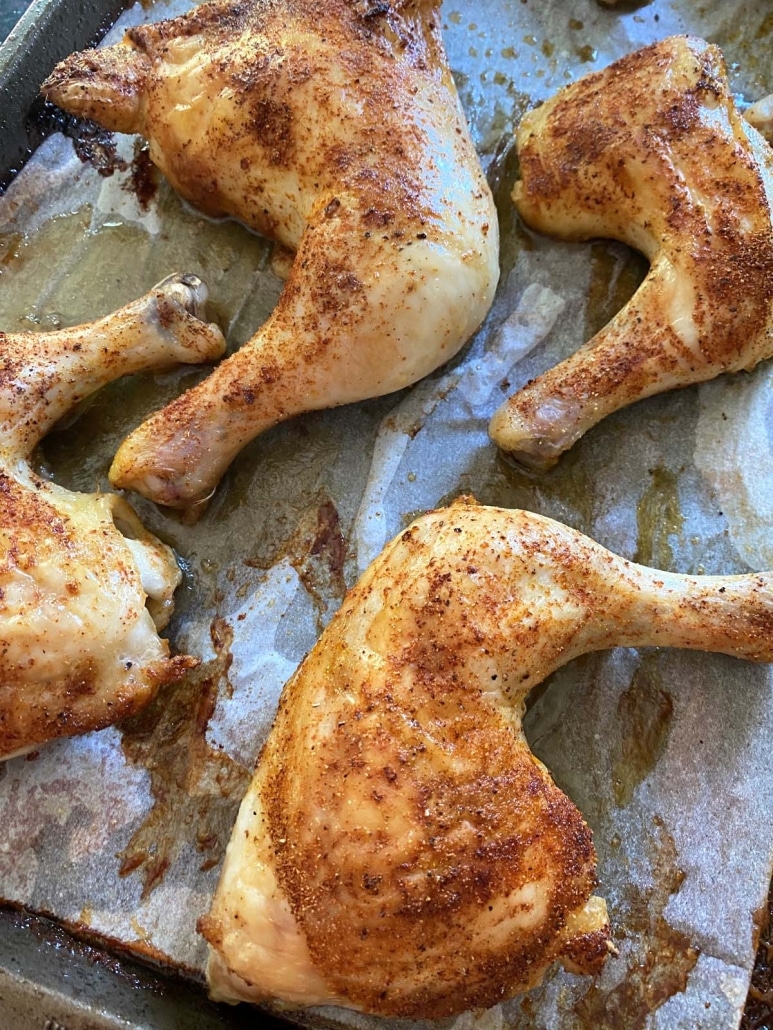 seasoned chicken leg quarters on baking sheet