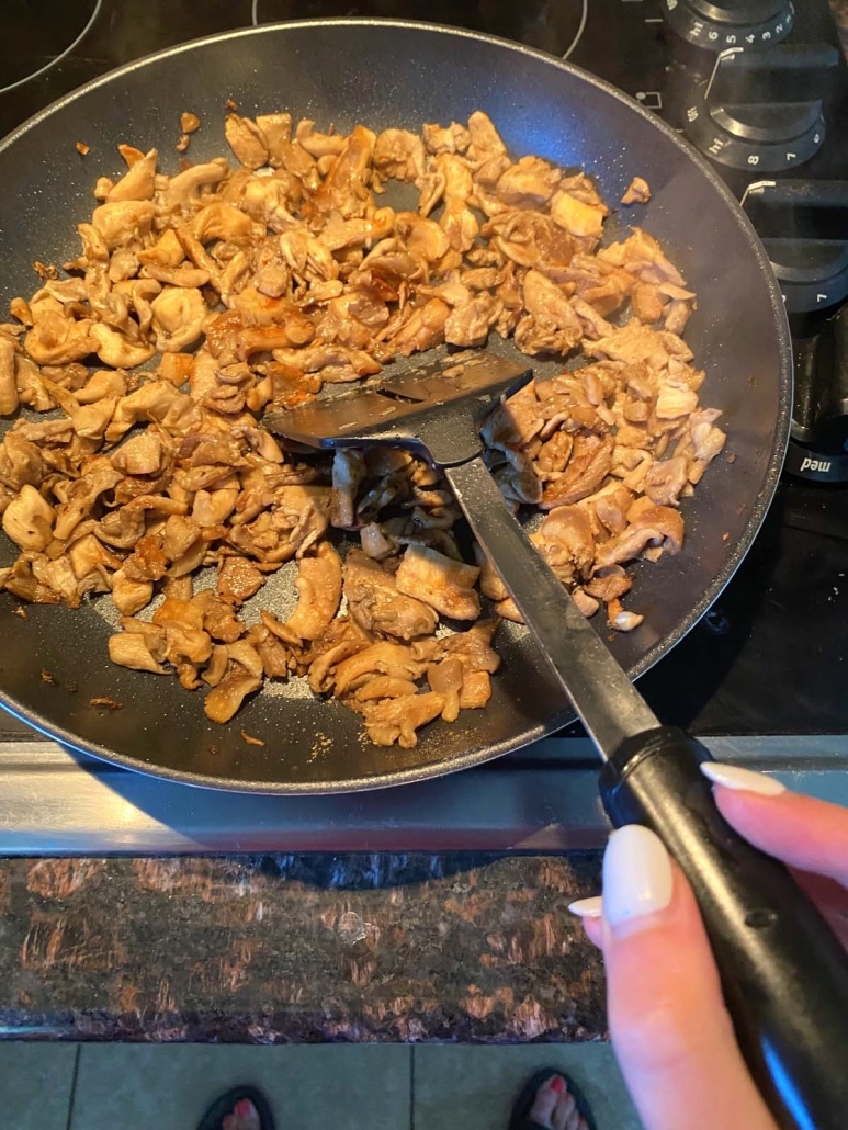 hand holding spatula turning over mushrooms for even cooking