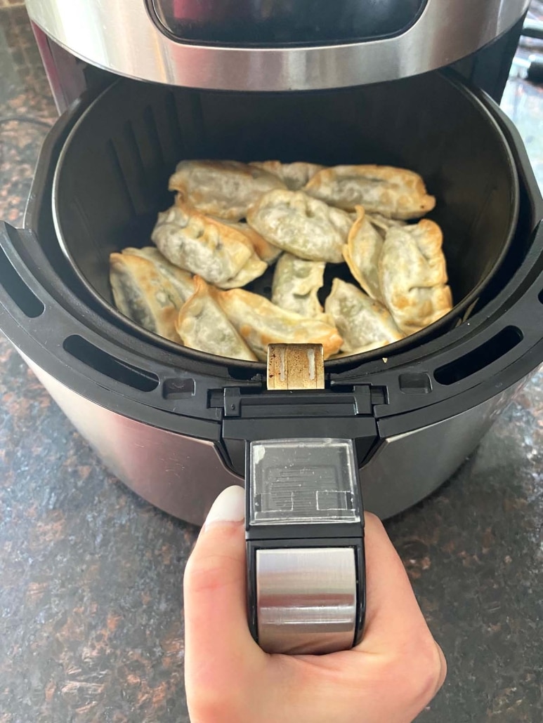 air fryer opened to show frozen gyoza crisping up inside