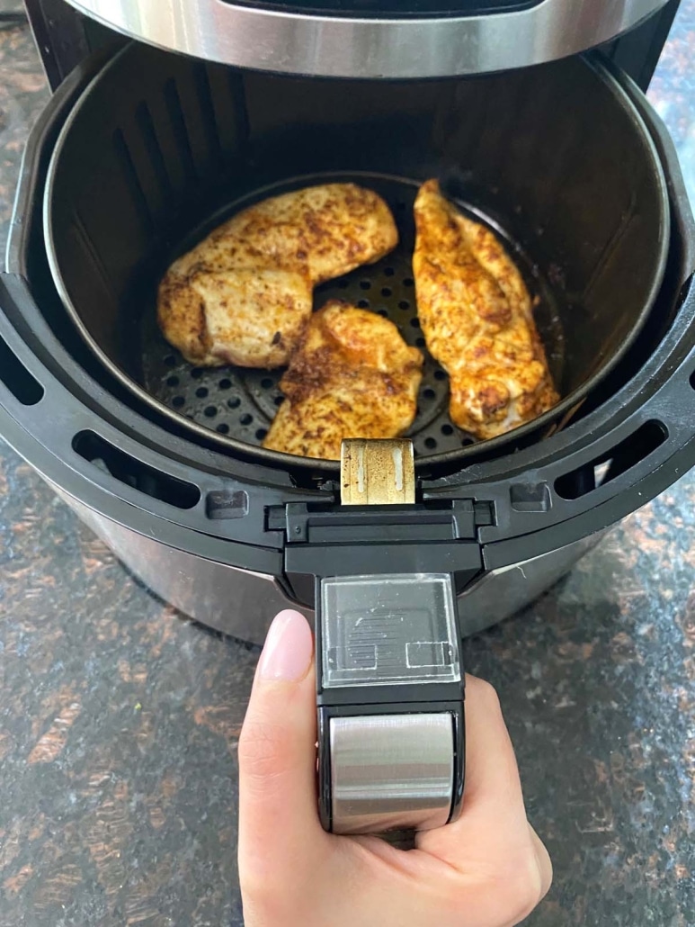 air fryer basket pulled open to show thinly sliced chicken breasts inside