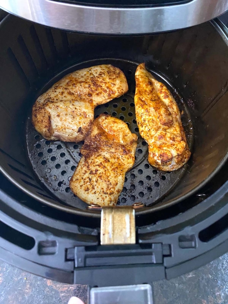 air fryer opened to show low carb thin sliced chicken breasts cooking inside