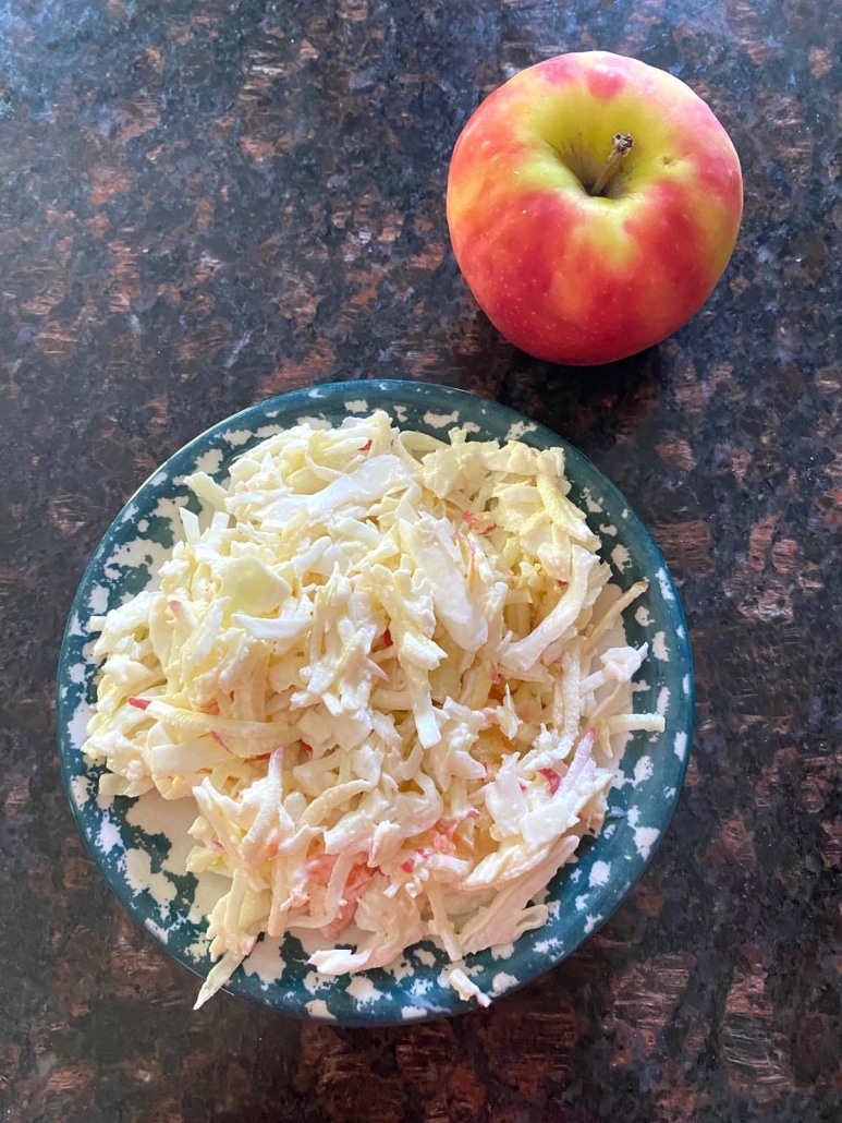 bowl of Apple Coleslaw next to an apple