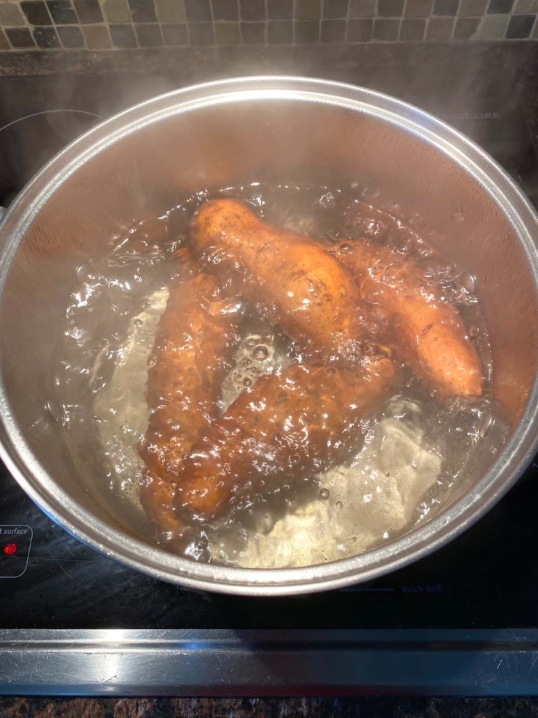 whole sweet potatoes cooking in a pot