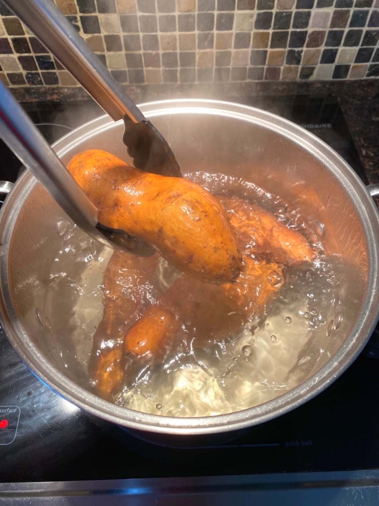 tongs holding a cooked sweet potato