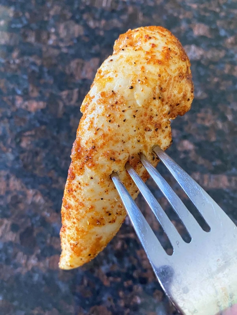 fork holding a tender pieces of broiled chicken
