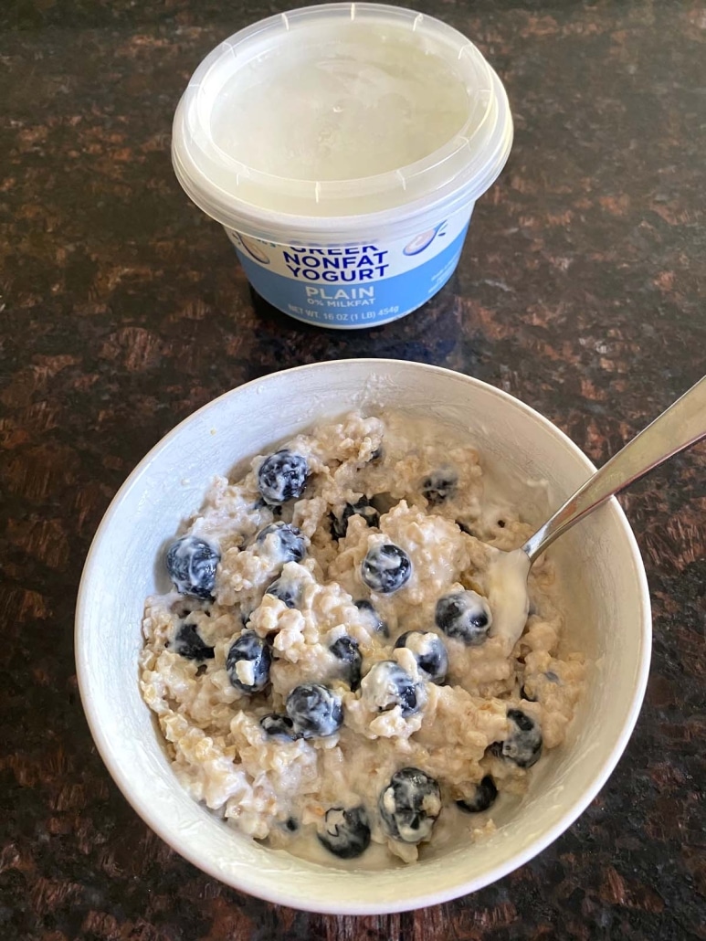 bowl of Greek Yogurt Oatmeal next to a container of Greek yogurt