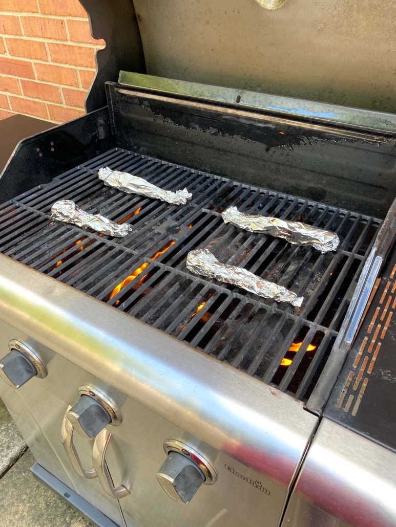 grill opened to show grilled carrots in foil packets