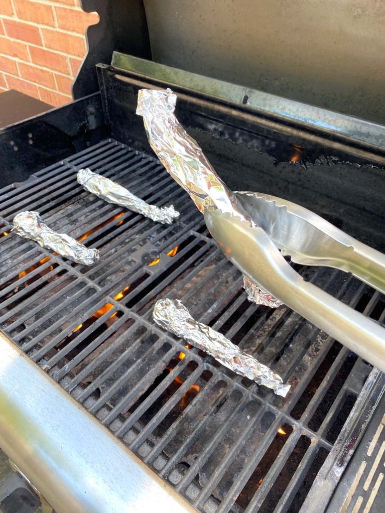 tongs holding foil wrapped carrot